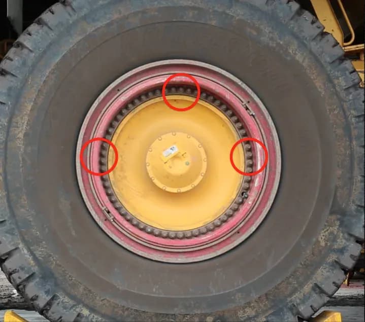 A haul truck wheel with every wheel nut fitted, three positions on the nave circled in red