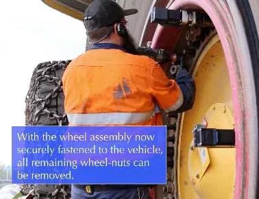 A tyre fitter removing the remaining wheel nuts with the retainers holding the wheel assembly